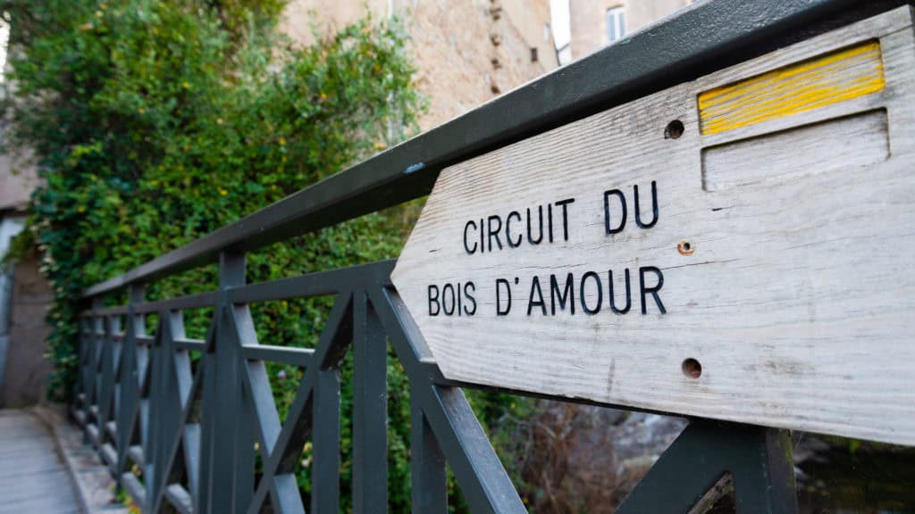 wooden indication arrow shaped in the village of pont aven, brittany, france, with the writing "circuit du bois d'amour" (circuit of the love forest).